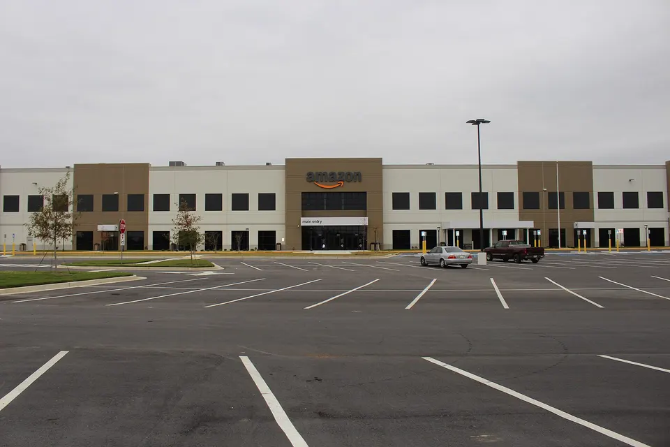 The exterior of a large Amazon fulfilment centre building with a car park in front